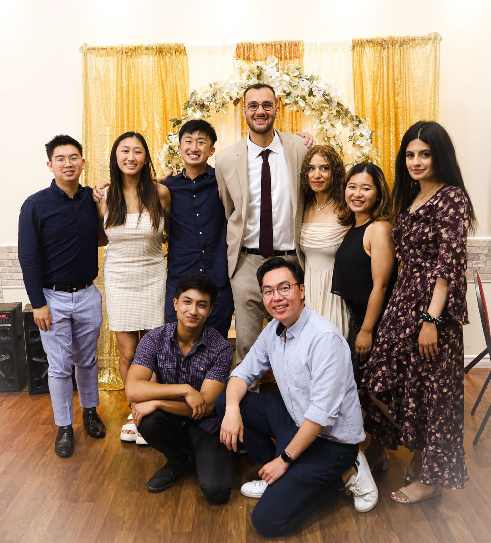 Formal group photo in front of ornate gold arch backdrop at special event.