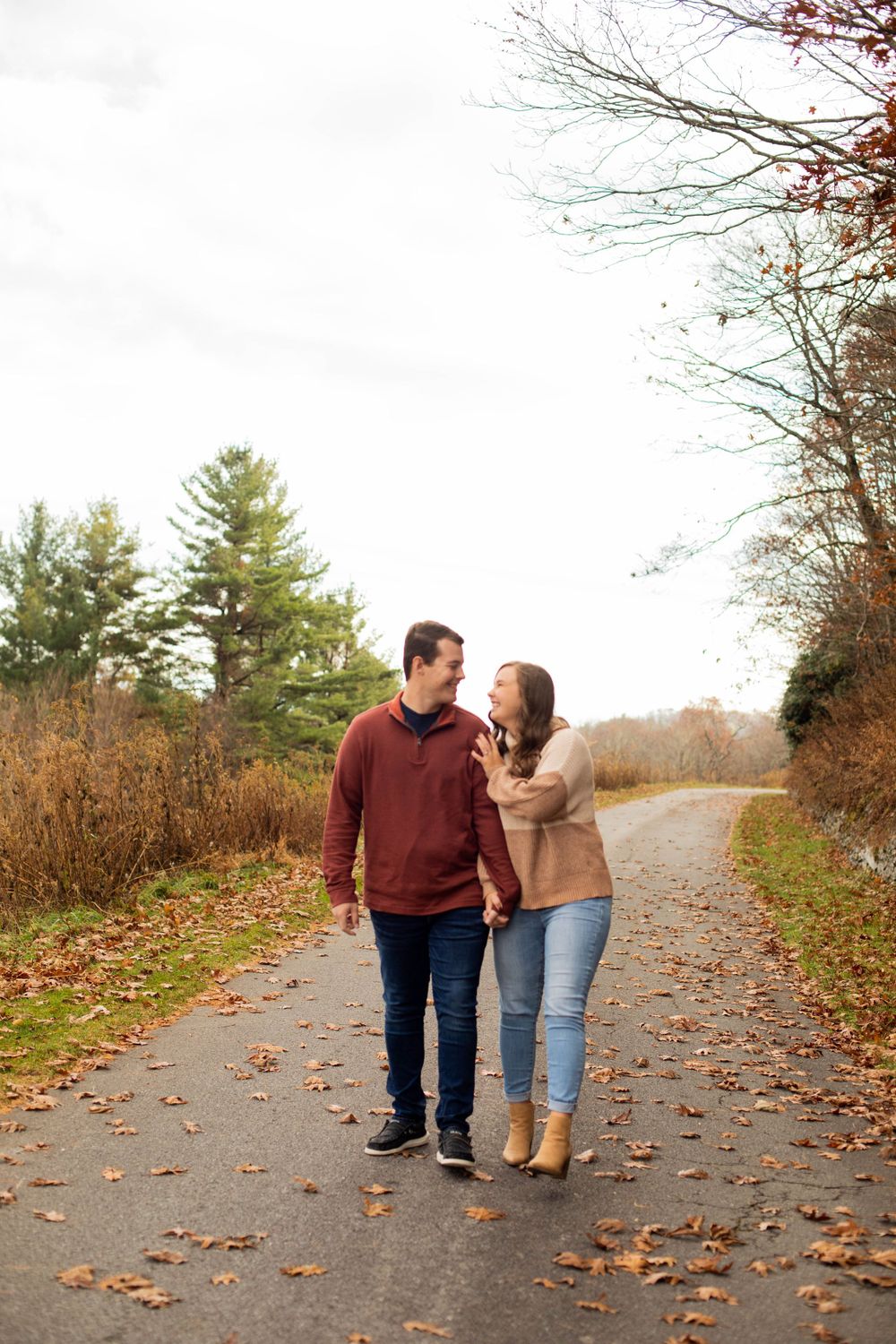 Couple walking together on leaf-covered path during autumn.