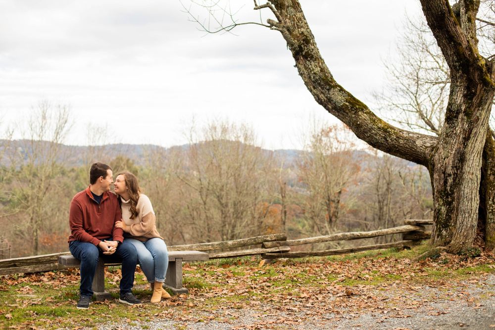A panoramic view of a couple embracing on a mountain overlook during autumn.