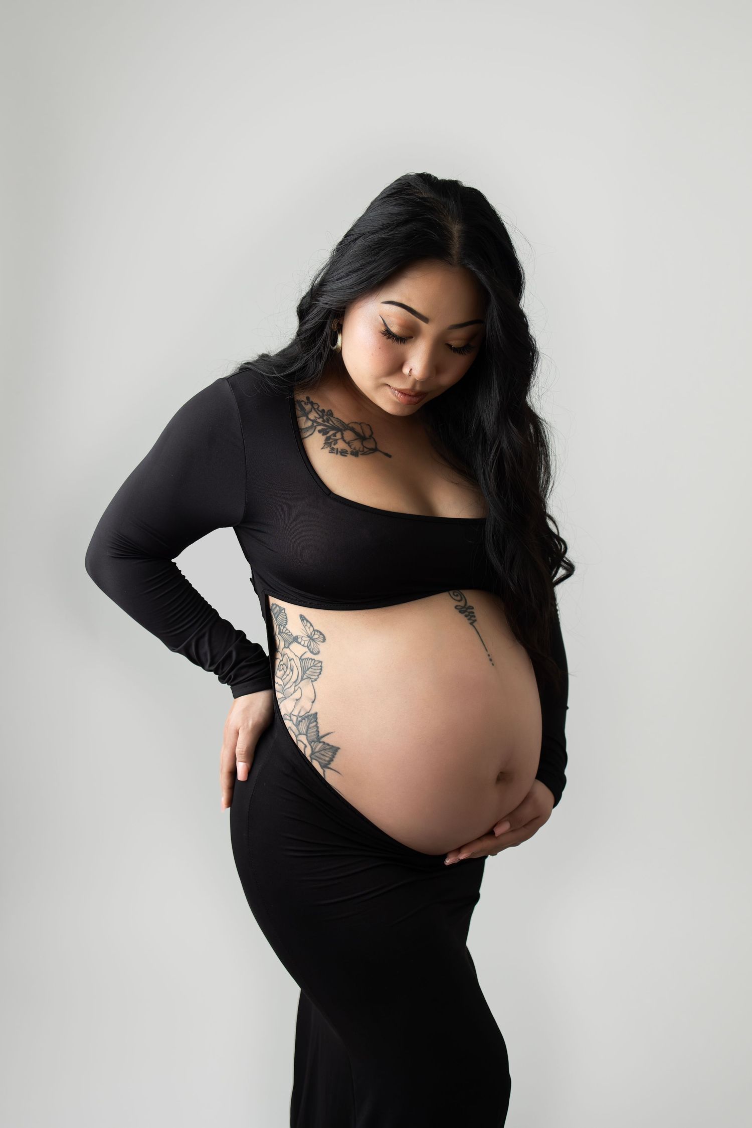 Maternity portrait against white background showing expectant mother in black outfit.