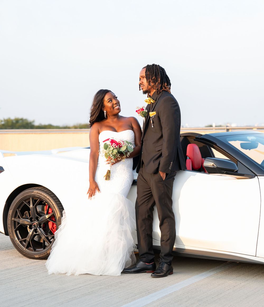 Bride and groom share a moment together while leaning against a white sports car.