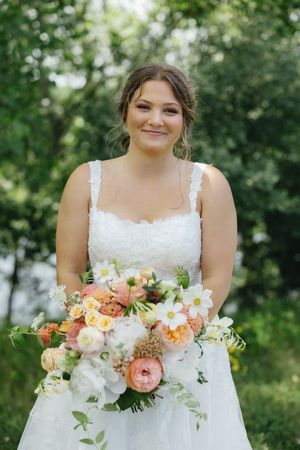 Beautiful wedding bouquet with coral peonies, white flowers and greenery creates an elegant spring garden arrangement.