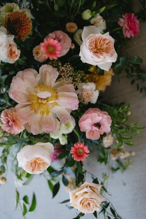 Delicate pink garden roses and coral flowers arranged in a romantic floral display against a white background.