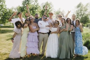 Wedding party celebrates outdoors in coordinated blush, lavender and sage green attire during summer celebration.