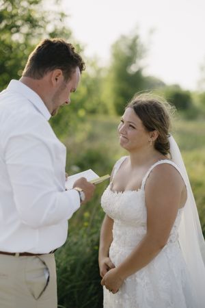 A couple shares a tender moment during their outdoor wedding ceremony as vows are exchanged in natural lighting.