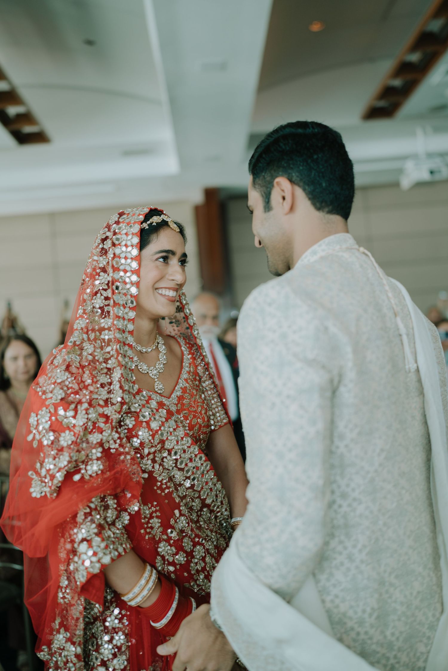 Traditional Indian wedding couple in ornate red and white outfits during ceremony.