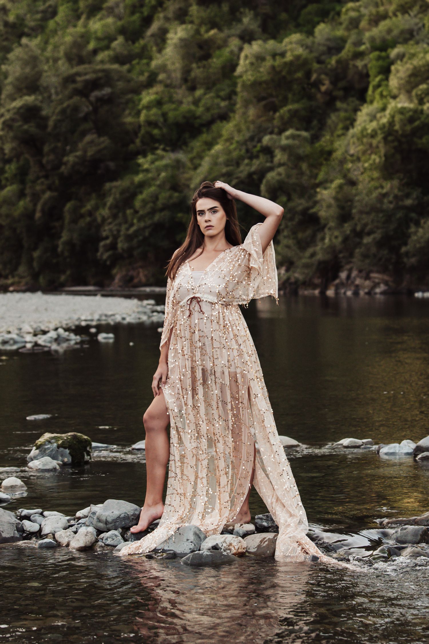 Champagne colored dress sparkles against rocky river landscape.