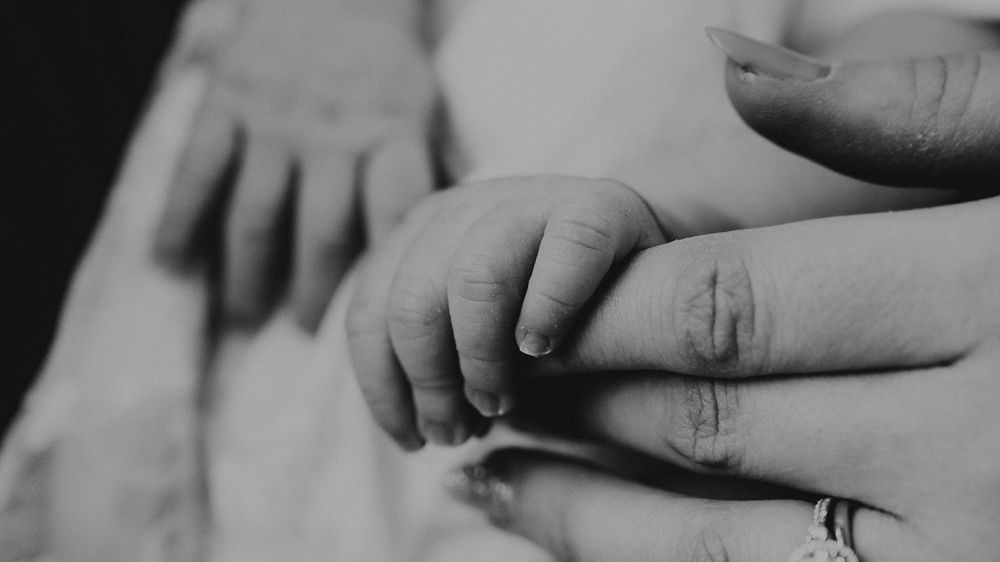 A black and white close-up series of hands with wedding rings.
