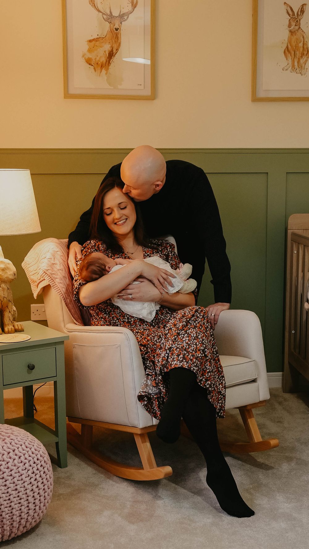 A tender moment captured in a nursery with rocking chair and animal artwork on walls.