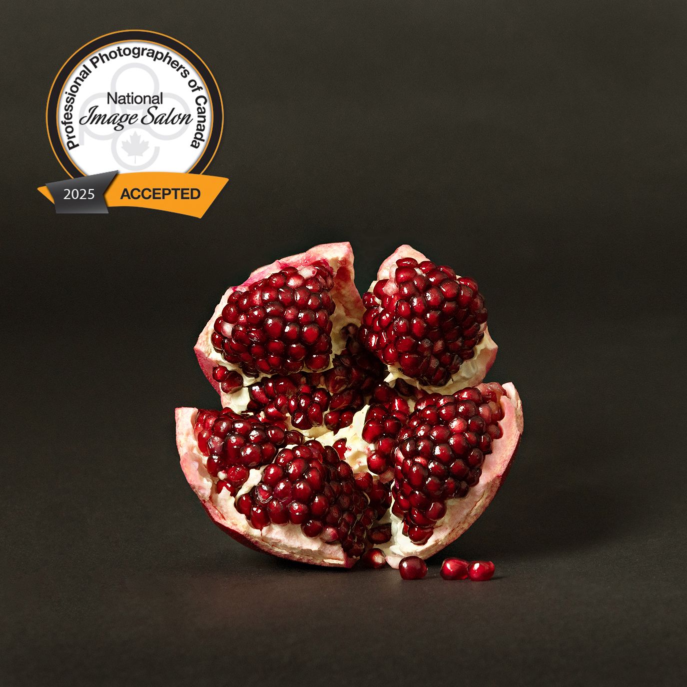 Close up of a split pomegranate showing bright red seeds against a dark background.