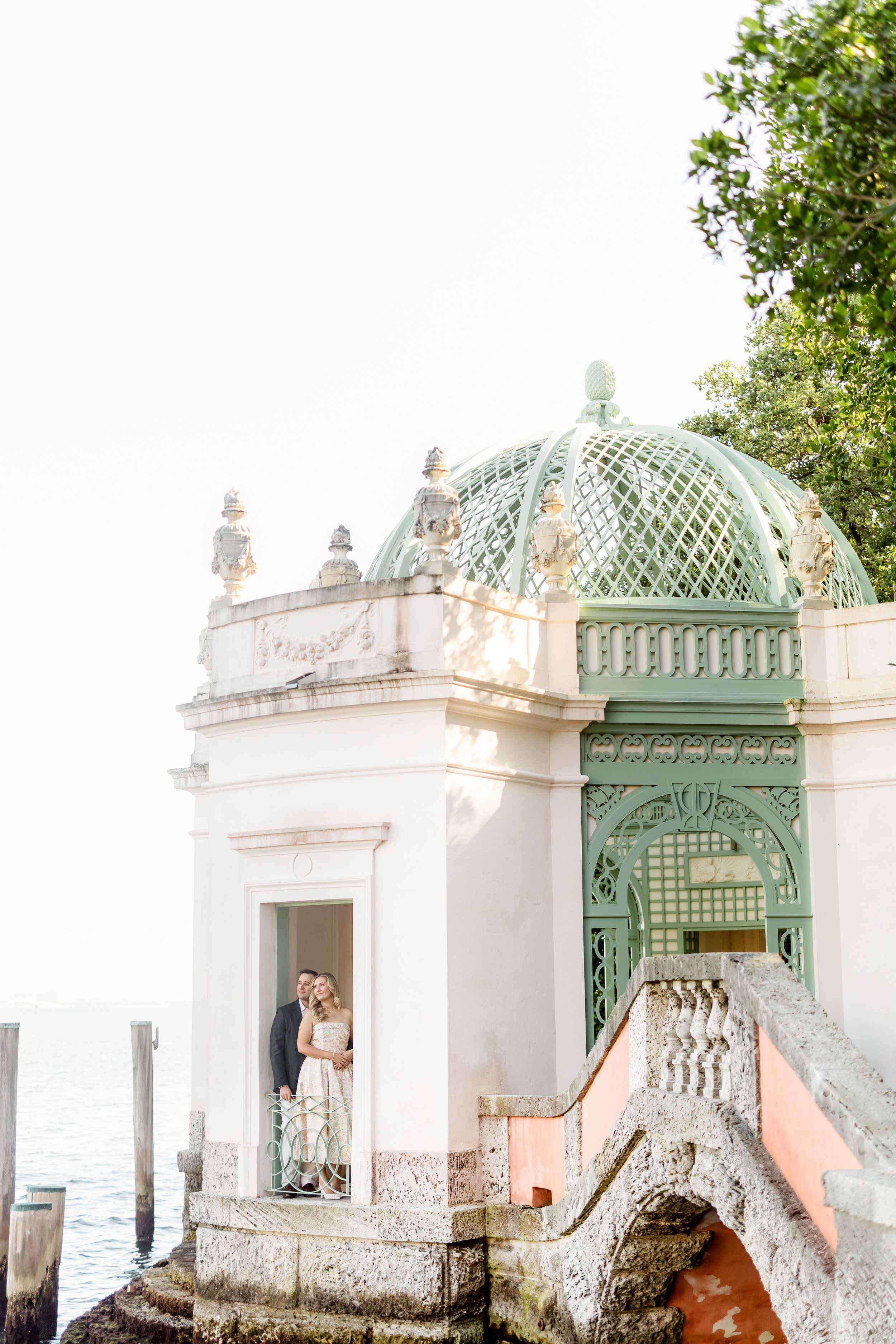 Ornate white and mint green gazebo with decorative architectural details and domed roof in a garden setting.