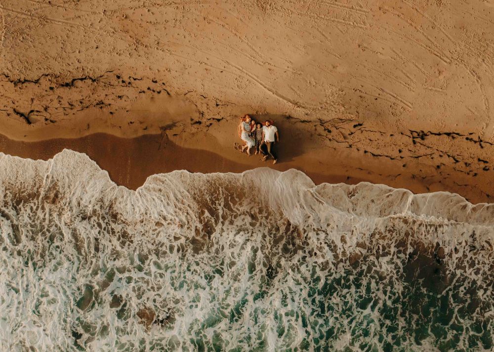 drone photo of family snuggling on the beach in california