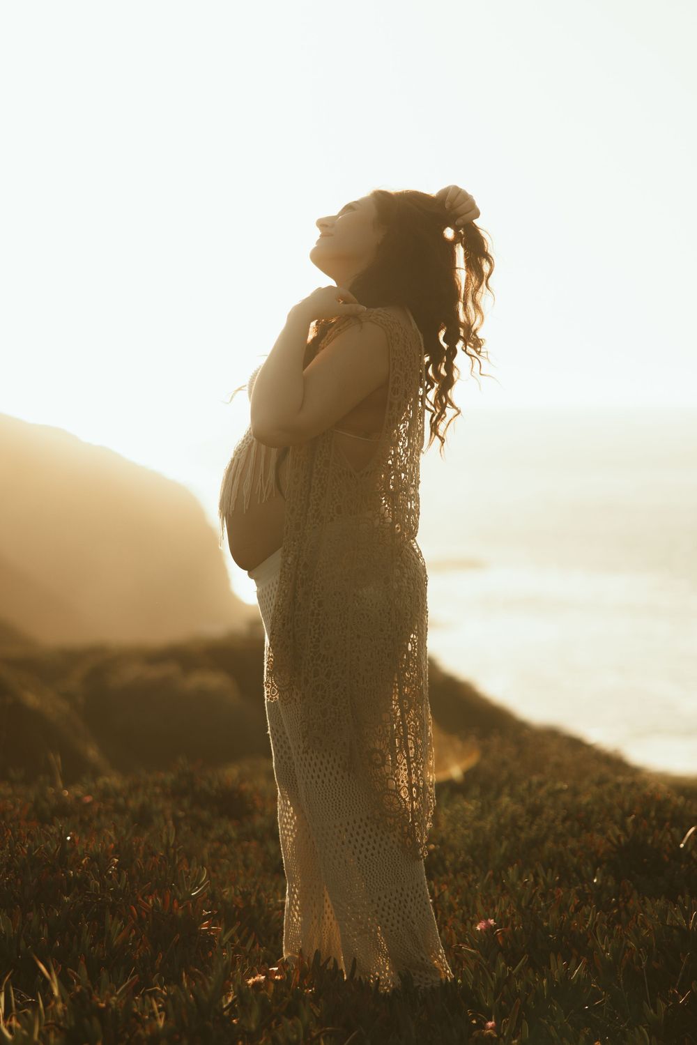 Ethereal silhouette of person in flowing dress against golden coastal landscape.