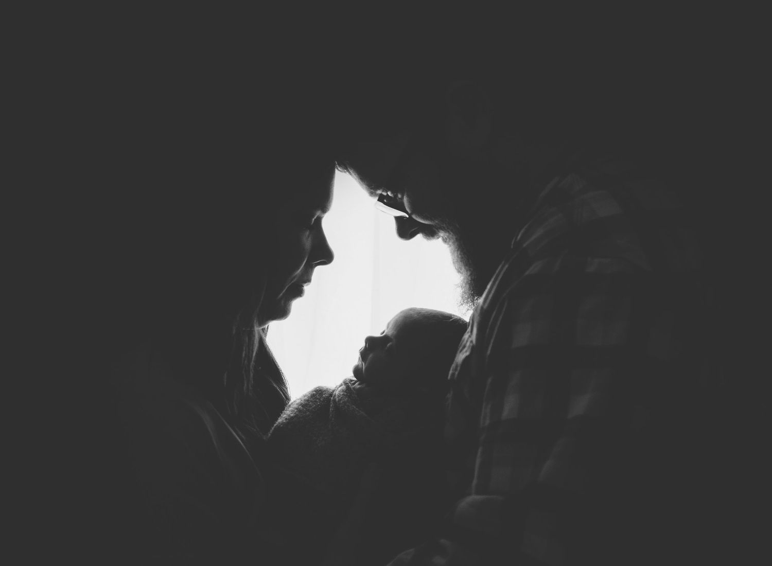 Dramatic silhouette portrait showing tender moment between two people.