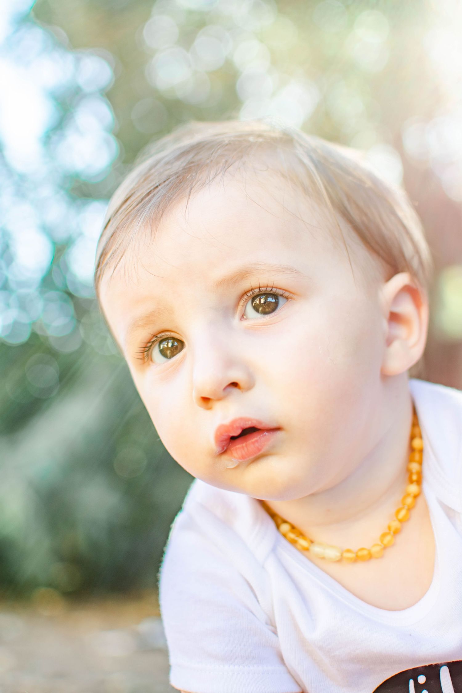 Close-up artistic portrait of a baby wearing white against a soft bokeh background.