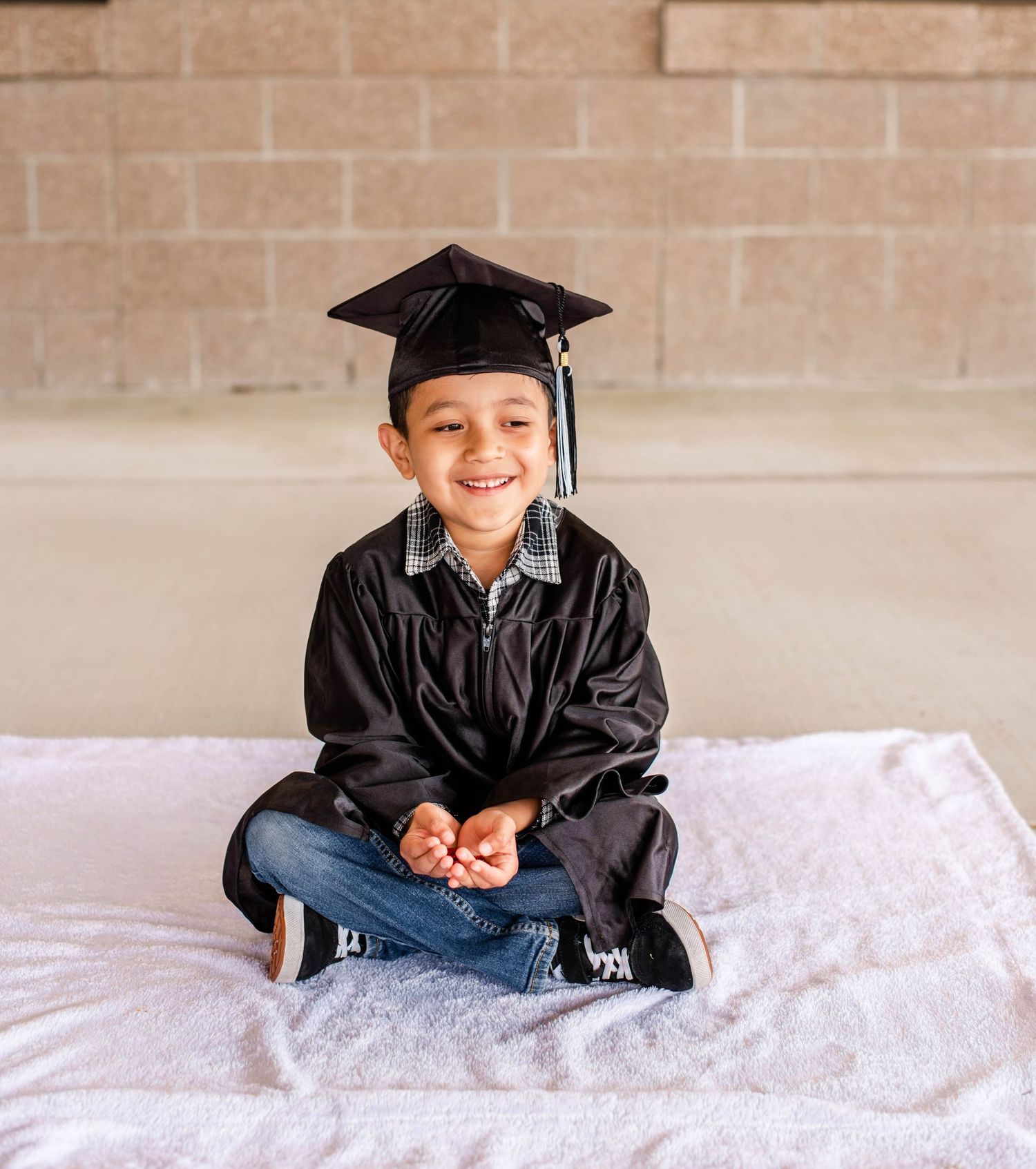 Graduate portrait session featuring black cap and gown on white backdrop.