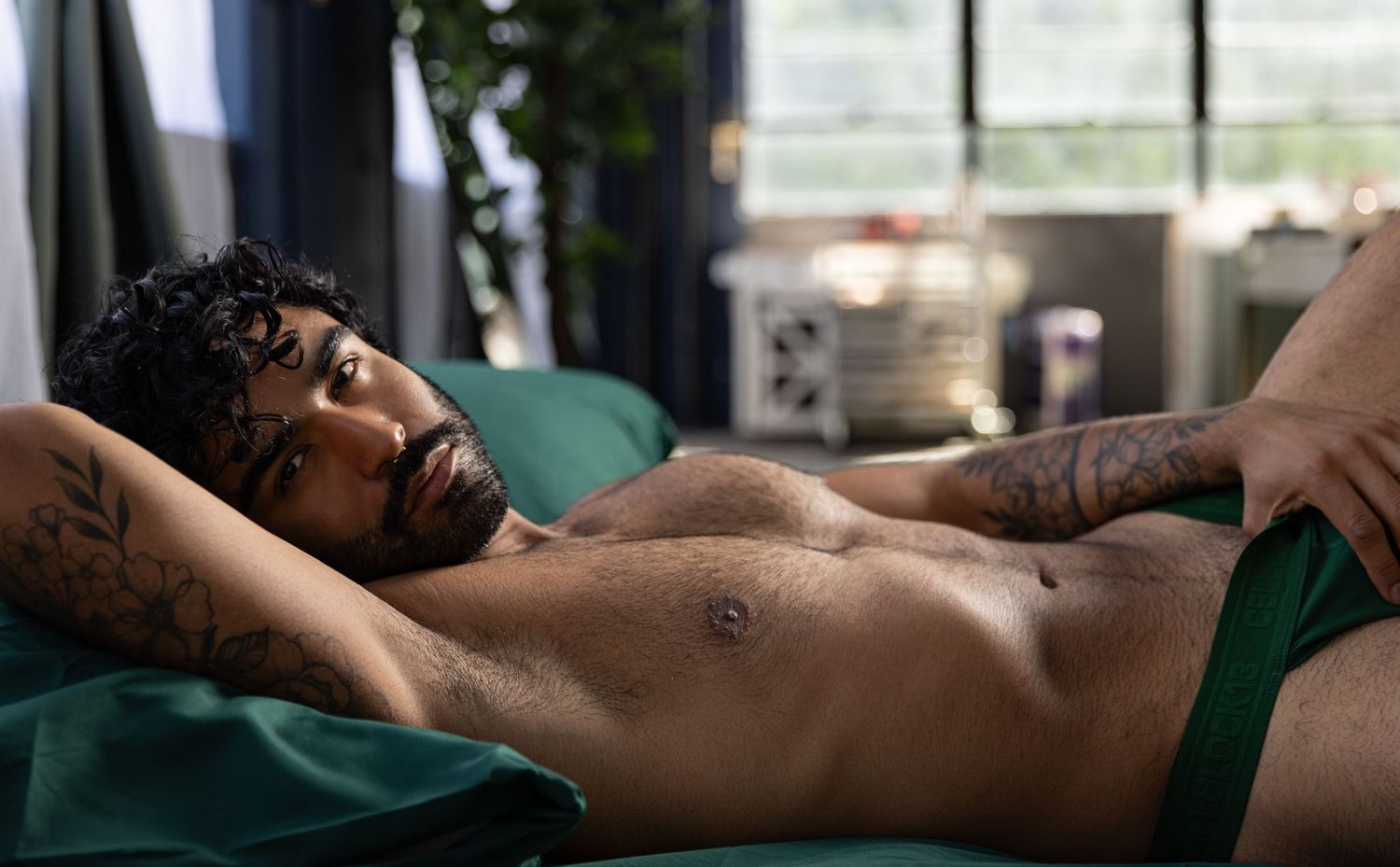 Handsome man lying in bed during session with Los Angeles boudoir photographer.