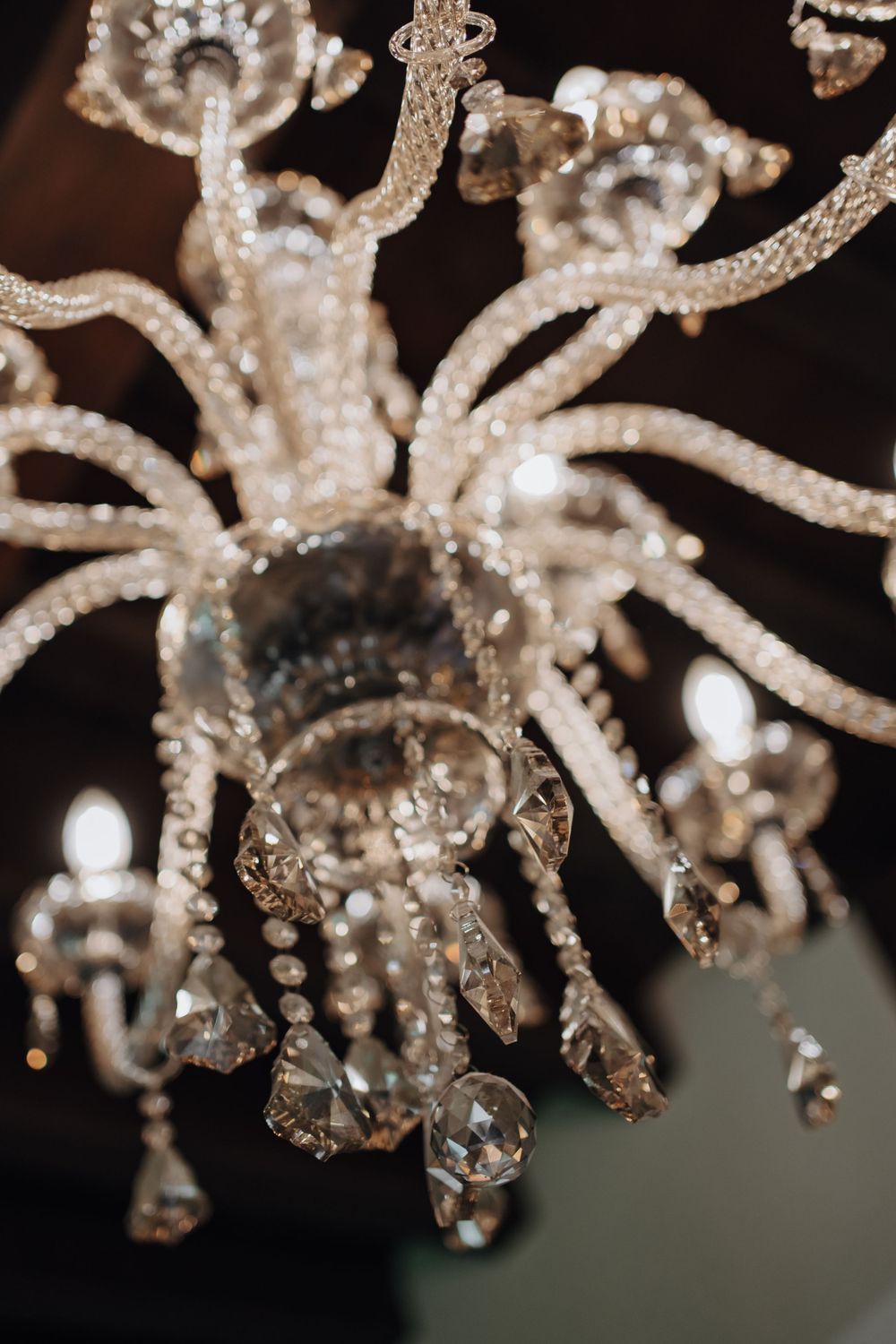 Crystal chandelier with ornate glass details and dangling prisms captured in soft focus.