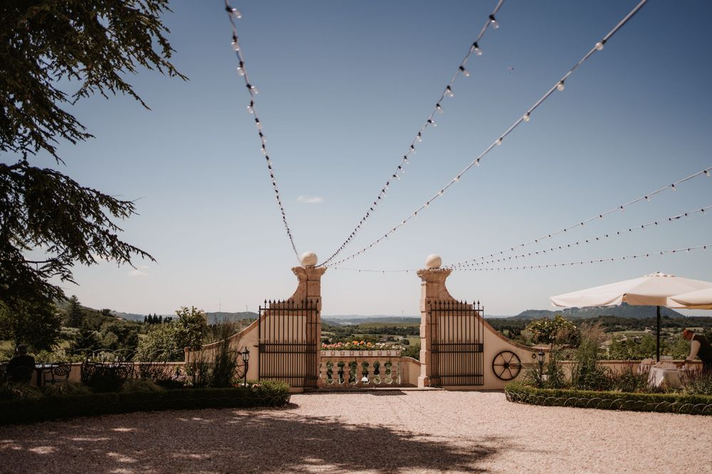 String lights hanging between stone pillars at an elegant outdoor venue entrance.