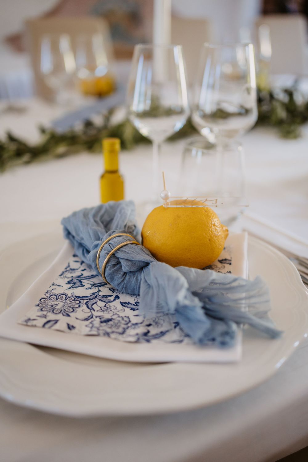 Elegant table setting with wine glasses and a lemon garnish on blue and white patterned napkin.