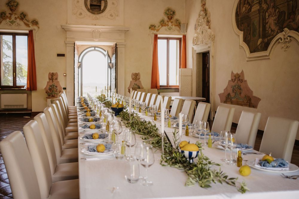 Elegant long dining table set for a formal event with white chairs and citrus centerpieces.
