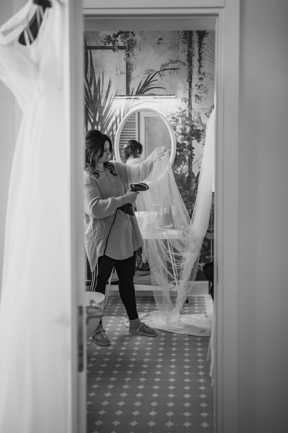 Elegant room interior with flowing white veil and botanical wallpaper captured through doorway in black and white.
