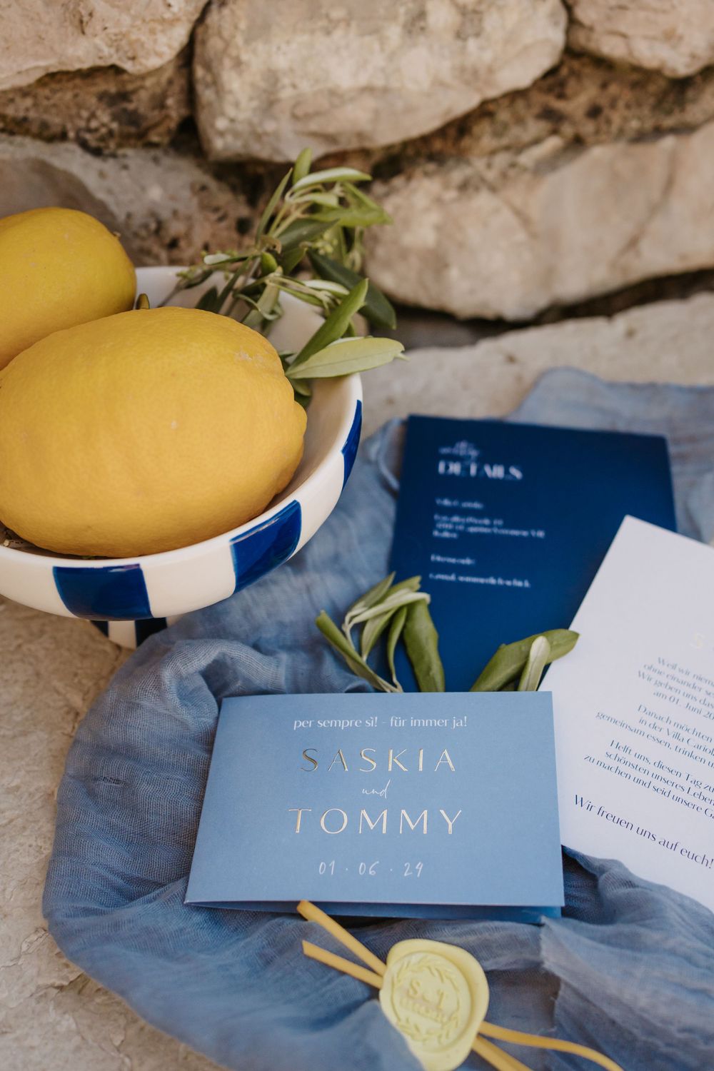 Wedding invitation for Saskia and Tommy with blue and white accents and fresh lemons in a striped bowl.