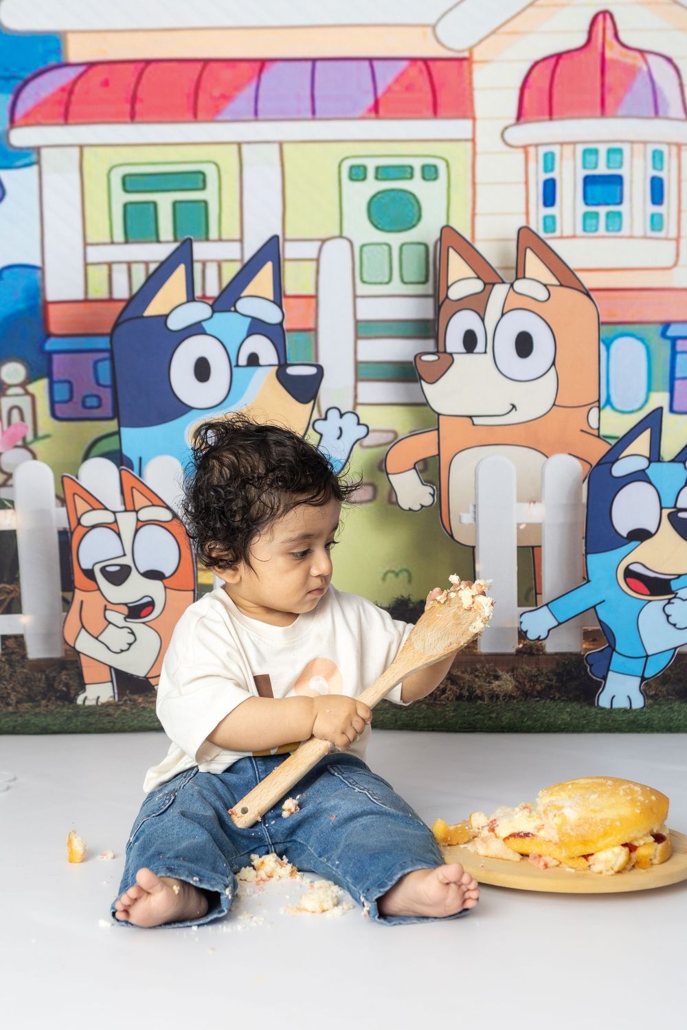 A cake smash photography session showing a child playing with frosting against a whimsical backdrop.