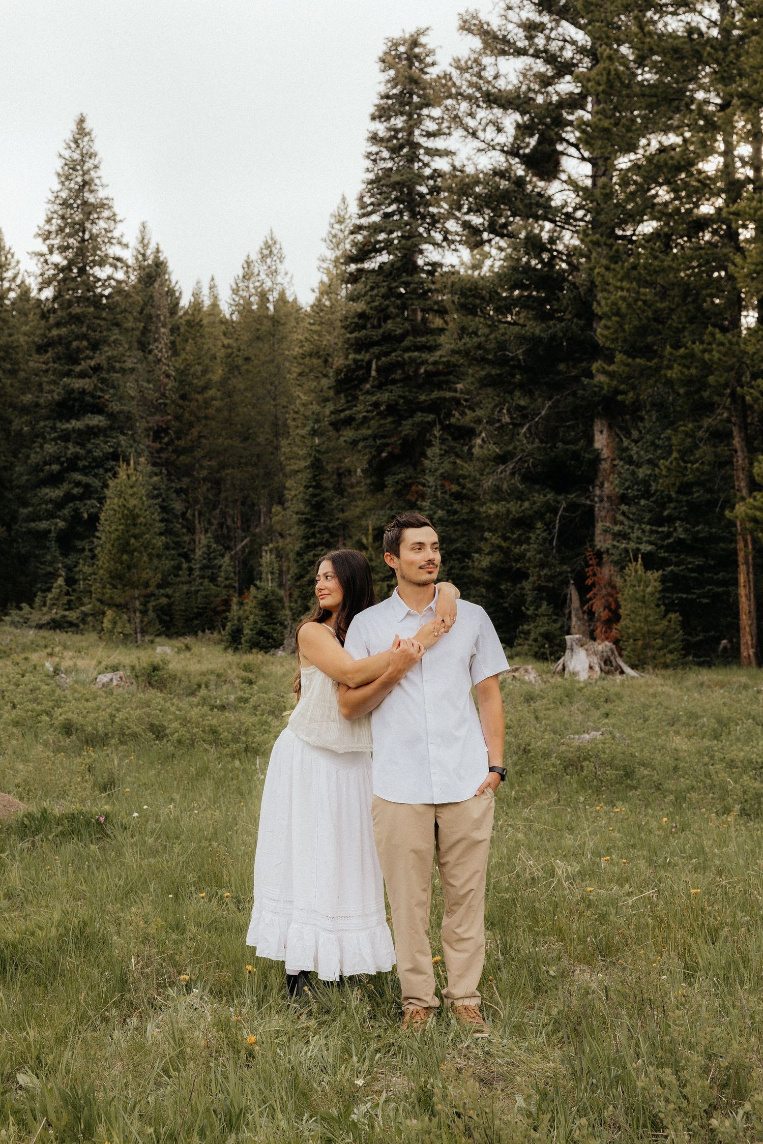 A tender embrace in a wildflower meadow surrounded by mountain scenery.