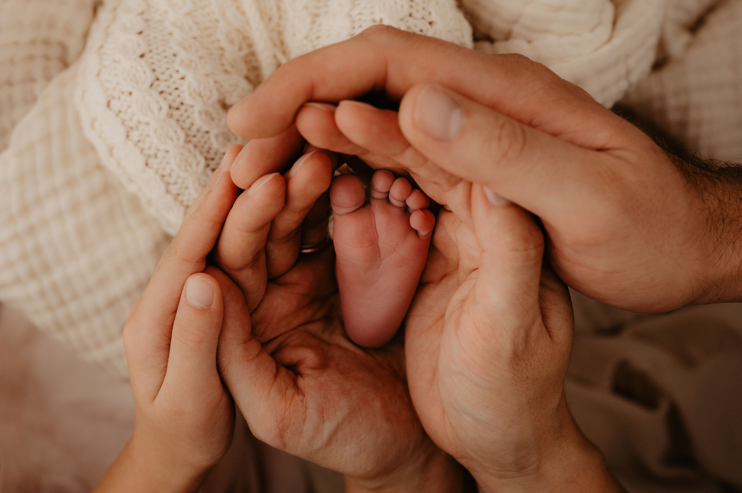 Close-up of holding hands with delicate tenderness against a light neutral background.