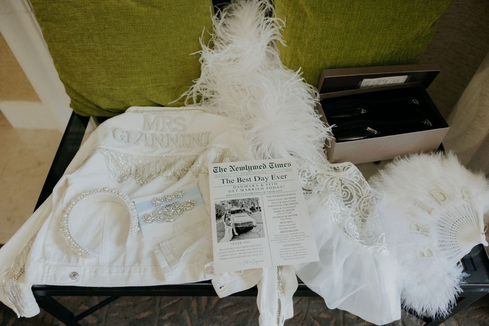 Wedding accessories and dress details laid out on green surface.