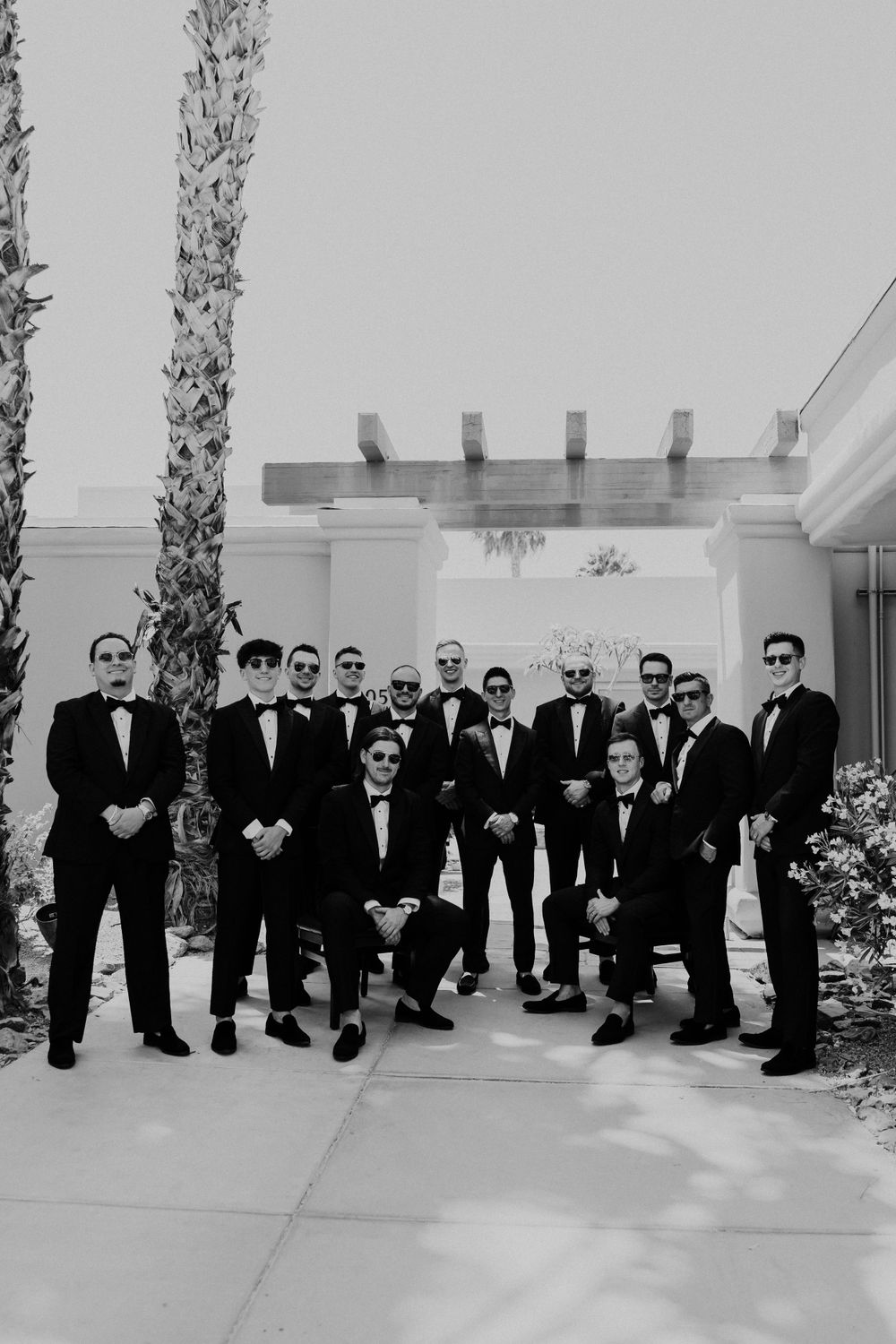 Groomsmen in black tuxedos posed together for formal wedding party photo.