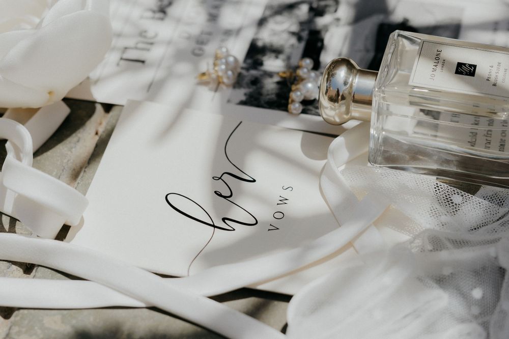 Wedding vow booklet and perfume bottle arranged with delicate styling details.
