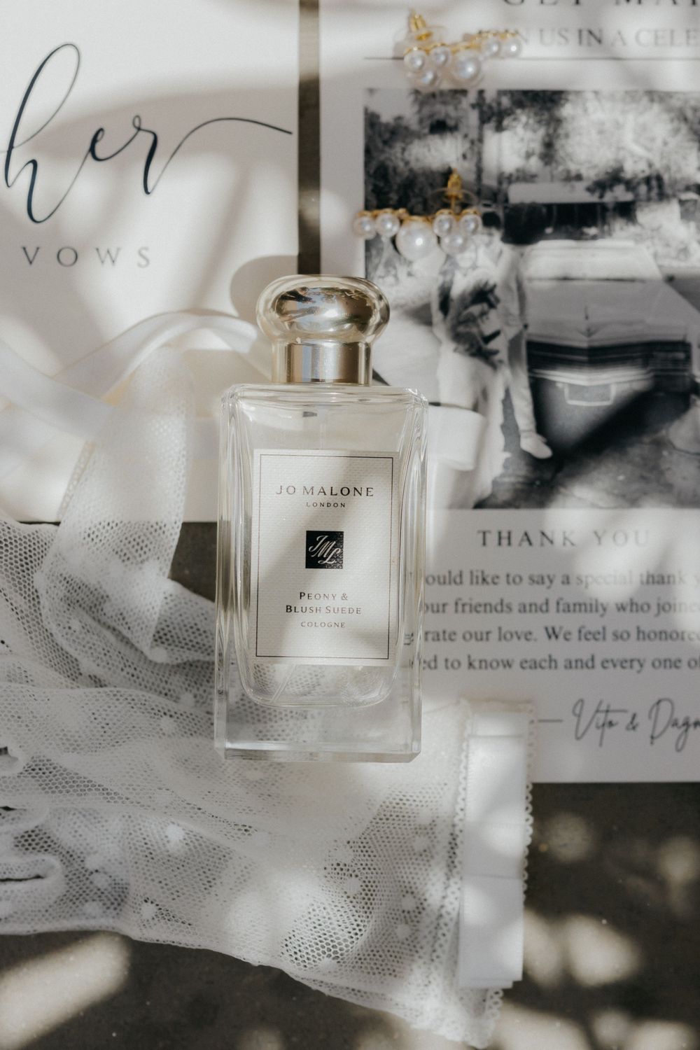 Jo Malone perfume bottle and wedding vows displayed on white fabric with elegant styling.