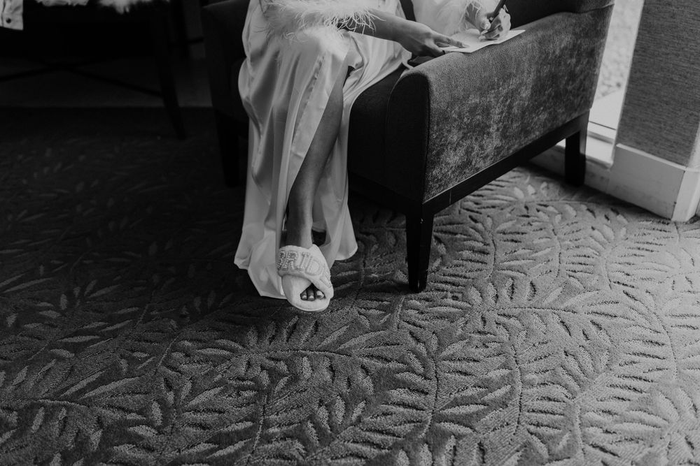 Close-up detail shot of wedding shoes and dress hem against a patterned carpet.