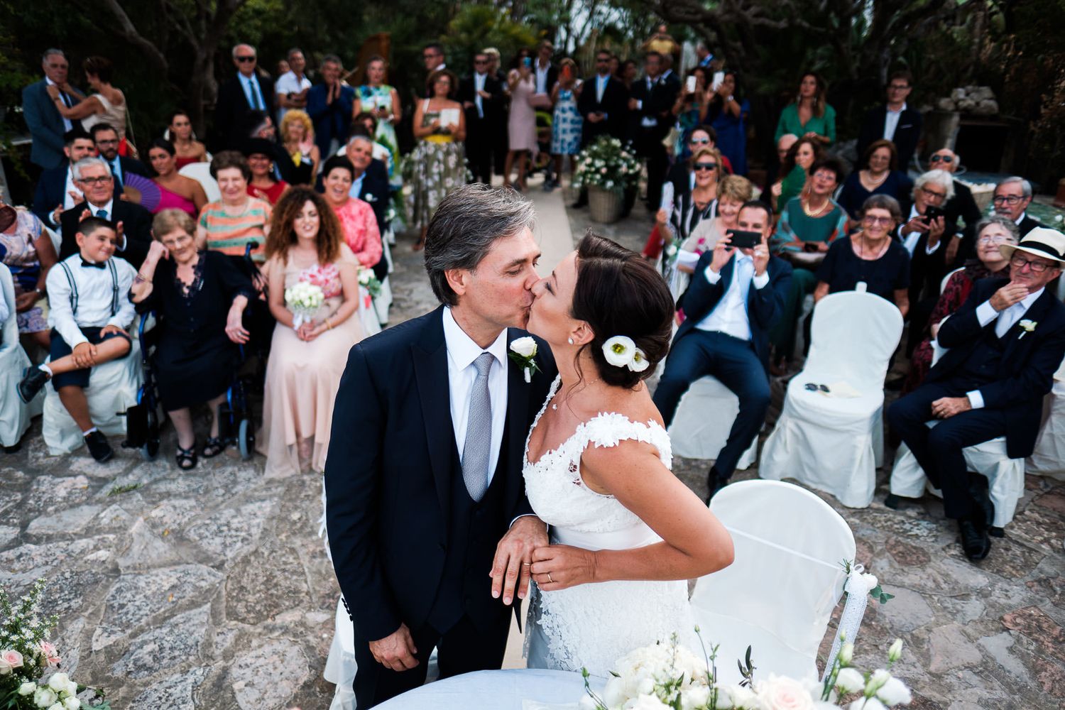 Wedding guests dancing and celebrating at an outdoor evening reception with string lights.