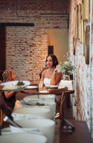 Guests sit at tables in a rustic dining room with exposed brick walls and elegant table settings.