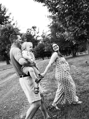 A carefree family plays and dances together outdoors on a summer day in a grassy field.