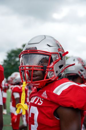Close-up of football player wearing red uniform and white helmet with protective face mask.