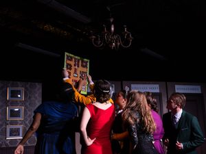 Couples dancing together in a dimly lit ballroom with purple and blue lighting effects.