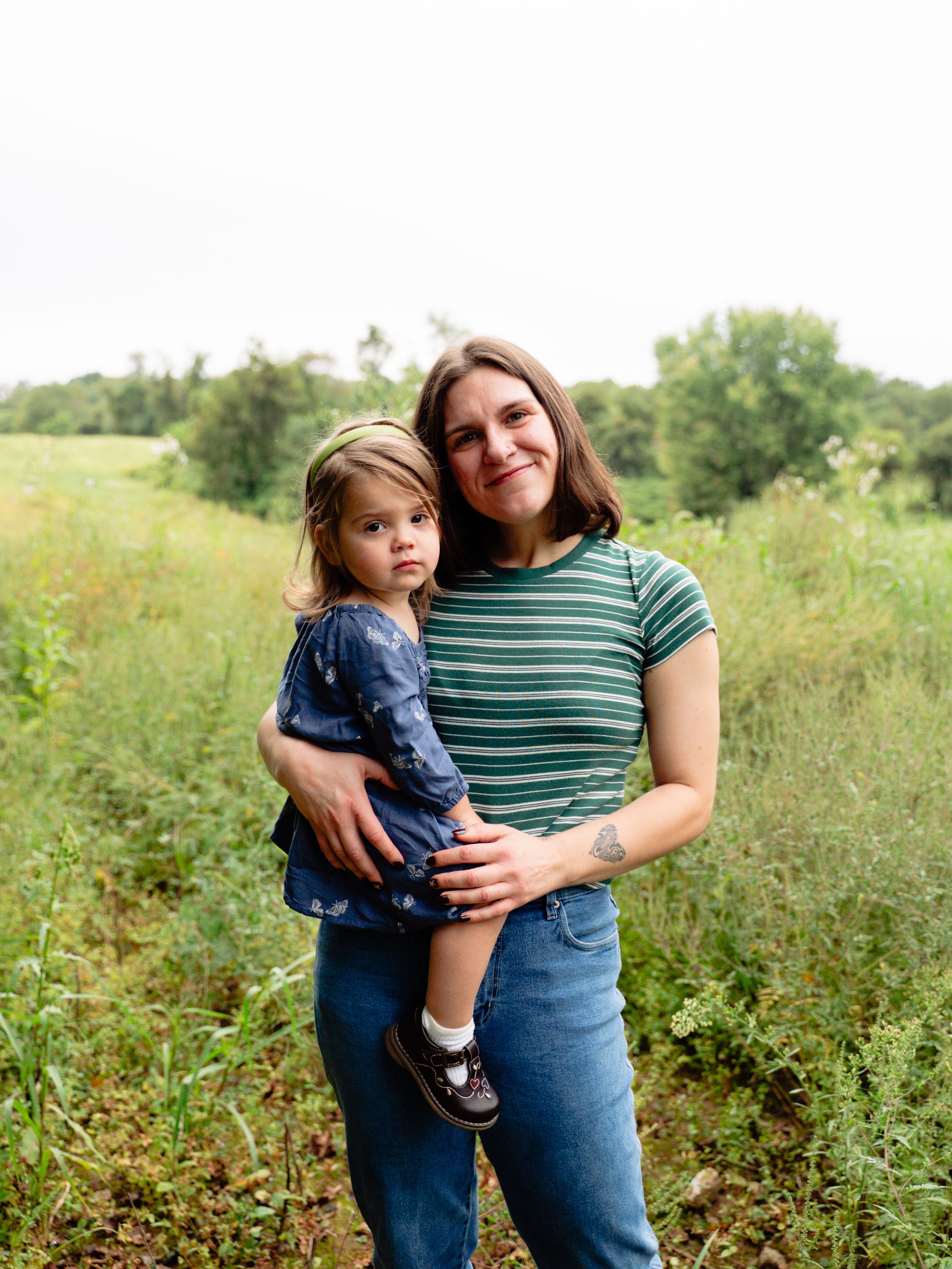 A heartwarming outdoor family photoshoot in a grassy meadow showing tender moments and embraces.