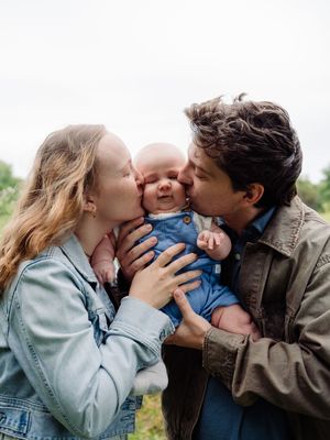 A loving couple sharing tender kisses with their baby in a series of outdoor family photos.