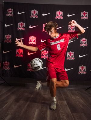 Soccer player in red uniform performs trick moves with ball against Nike-branded backdrop.