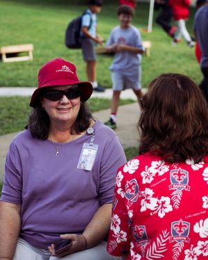 People wearing purple and red Hawaiian print shirts gather outdoors at a casual summer event.