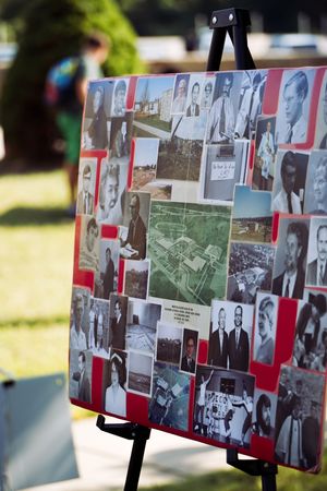 A display board with black and white historical photographs arranged in rows with red accents visible outdoors.