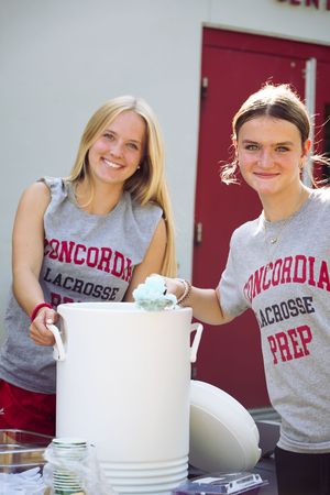 Students in Concordia lacrosse shirts stack white cups while participating in a team activity.