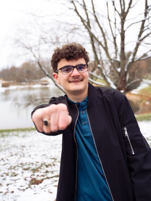 A person in a black jacket and glasses stands in a snowy landscape while making pointing gestures in a sequence.
