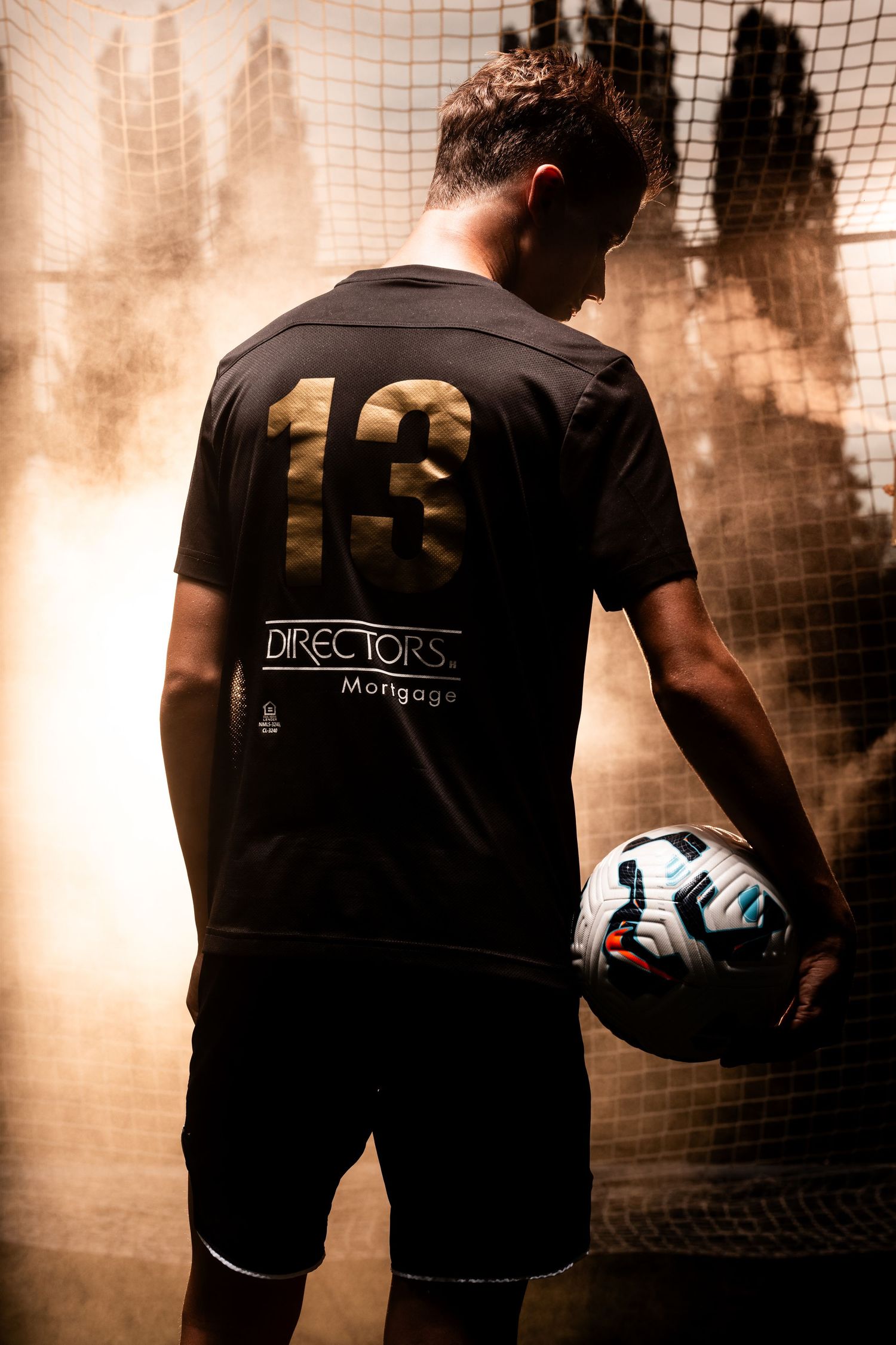 A silhouetted athlete crouches on a diving platform in dramatic blue lighting before a competitive dive.