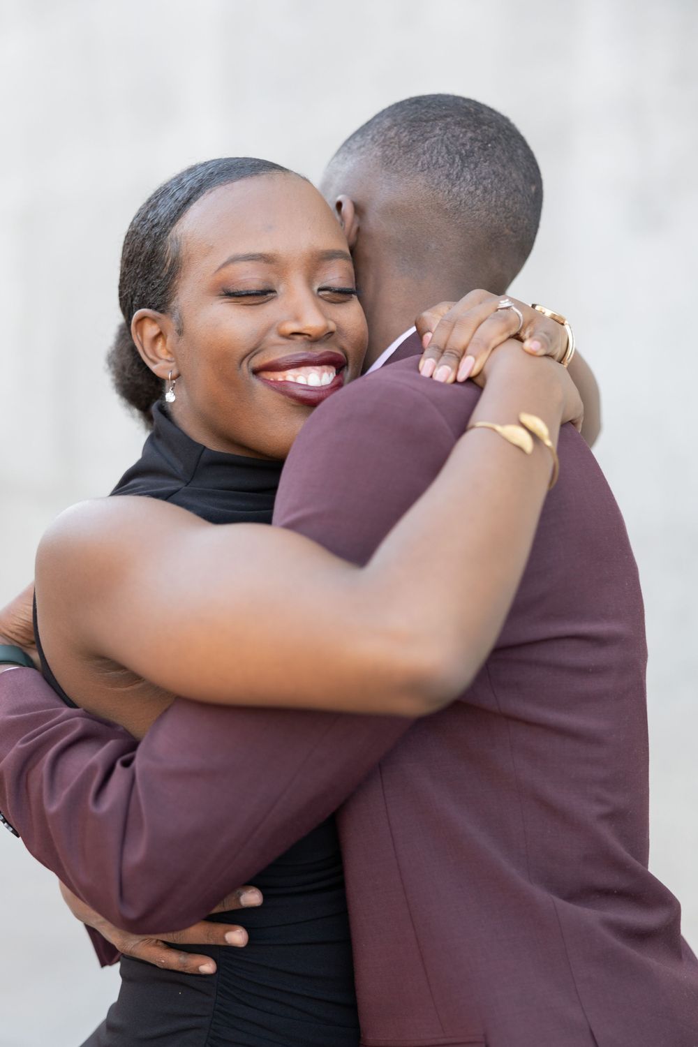 A romantic embrace between a couple, with the woman in black smiling joyfully.