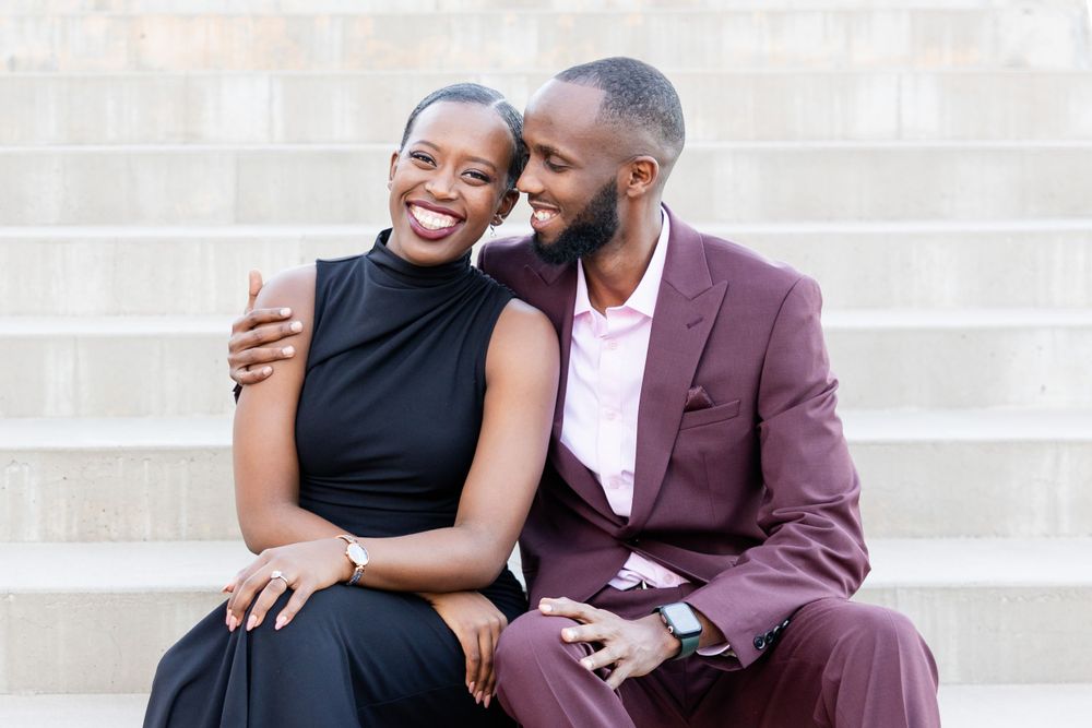 A couple shares a tender moment while seated on concrete steps outdoors.
